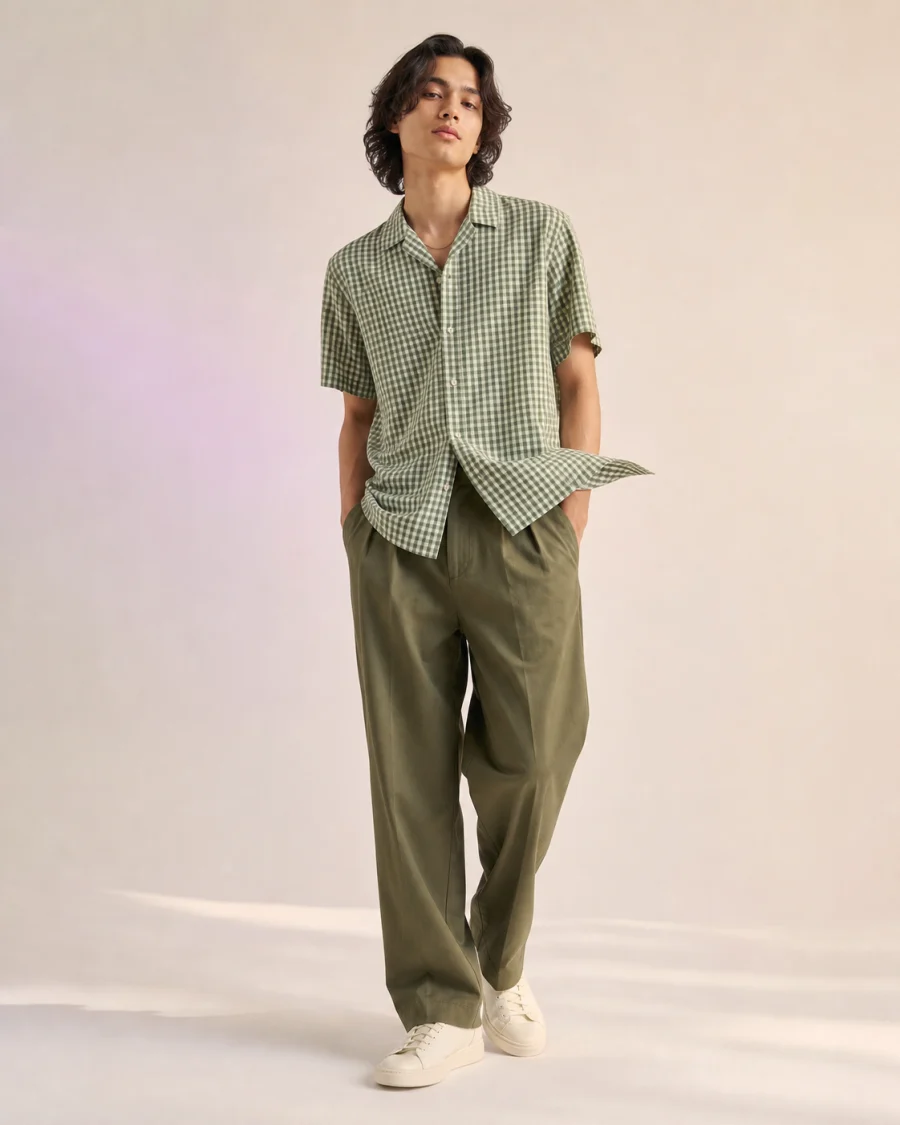 Illustrative fashion editorial of a model wearing a green gingham shirt and olive trousers